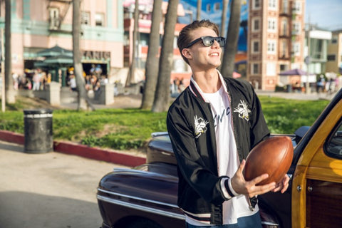 guy in black jacket wearing black sunglasses playing with a football