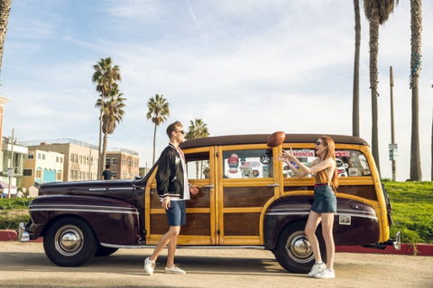 couple standing on the side on their vintage wagon both wearing sunglasses
