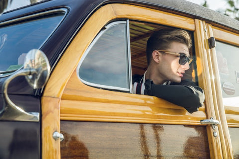 guy in black jacket wearing black sunglasses driving his vintage wagon