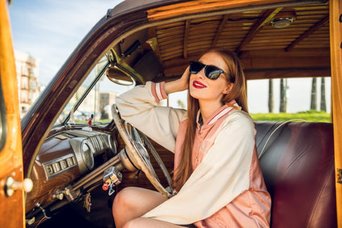 girl in a pink and white jacket wearing a wooden sunglasses in the shade of black posing in a wagon