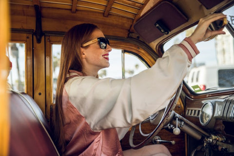 girl in a pink and white jacket wearing a wooden sunglasses in the shade of black driving a wagon