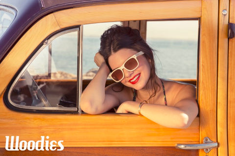 girl wearing wooden white sunglasses inside a vintage wagon smiling