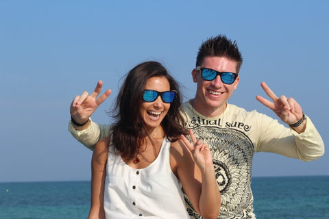 guy and girl wearing matching blue sunglasses posing for a shot