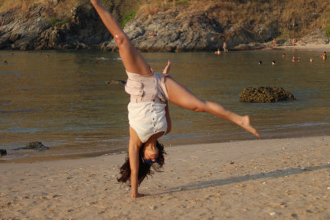 girl in white wearing sunglasses doing a one hand cartwheel