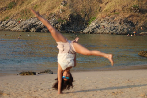 girl in white wearing sunglasses doing a one hand cartwheel