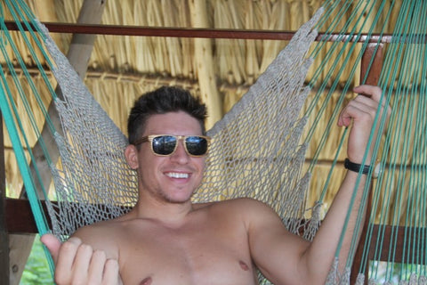 guy wearing a wooden sunglasses relaxing in a hammock 