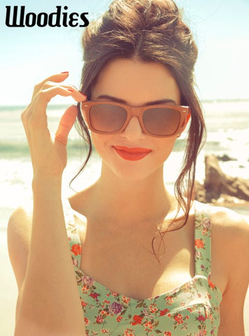 girl in floral top wearing brown wooden sunglasses