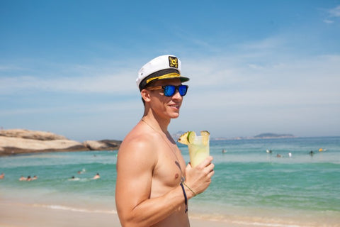 captain wearing wooden sunglasses enjoying the beach and his drink