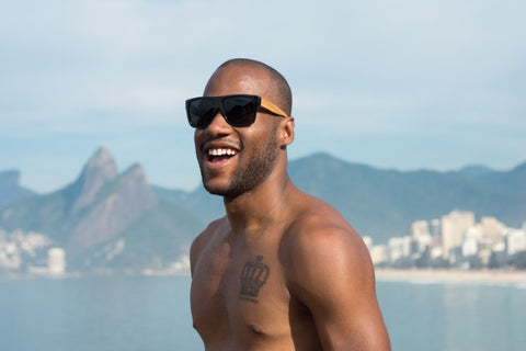 topless guy with crown tattoo on chest wearing wooden black shade sunglasses