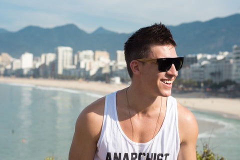 guy in white tank top wearing wooden black sunglasses