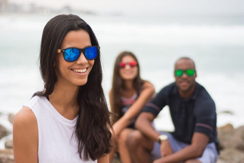 girl in white tank top wearing a sunglasses in the shade of blue with her friends behind her