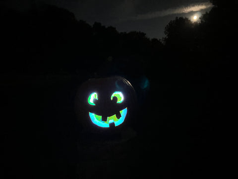 A pumpkin carved with a goofy face glowing blue.