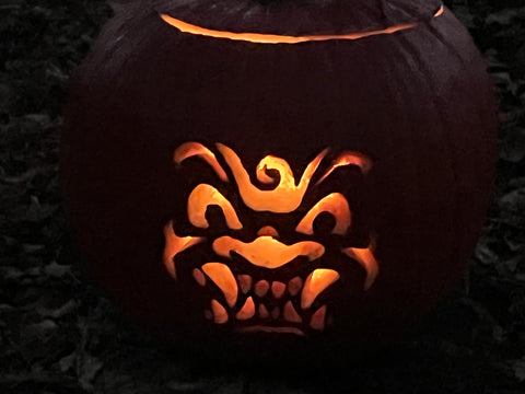 A pumpkin carved with a what looks like a mythical animal face..