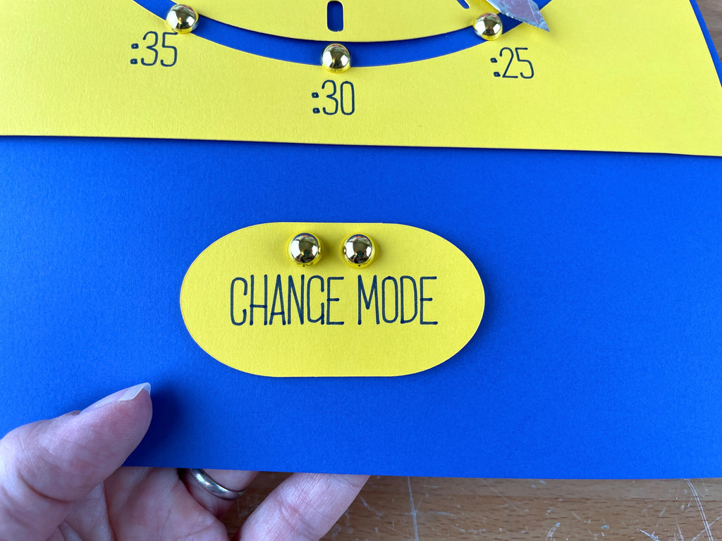 Circle with "Change mode" written and two brass fasteners above the words