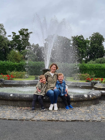 Carol with her sons sitting in front of a fountain