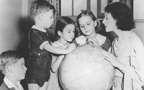 Vintage teacher showing students landmarks on a globe