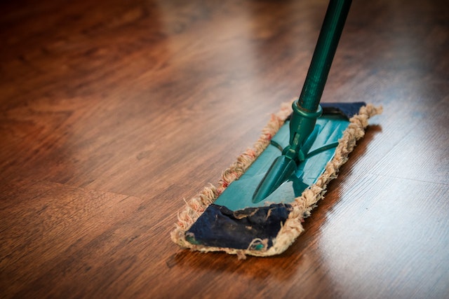 : Before you apply the other home staging tips for spring we will give you, it’s important to clean everything first. Alt text: A mop on a wooden floor