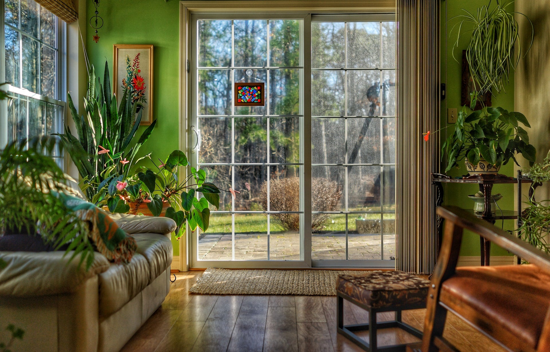 Caption: If you want to bring more natural elements into your home, open those heavy curtains and let the sunshine in! A large window in a living room filled with house plants and other natural elements.  Photo by Edan Cohen on Unsplash