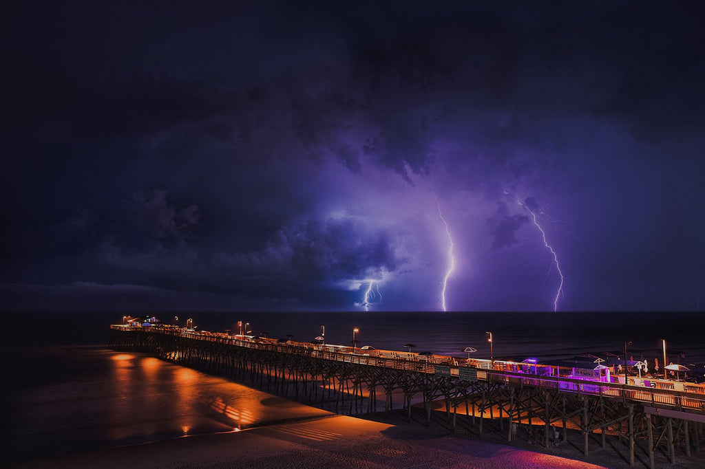 Night photo of a pier with lightning in the background