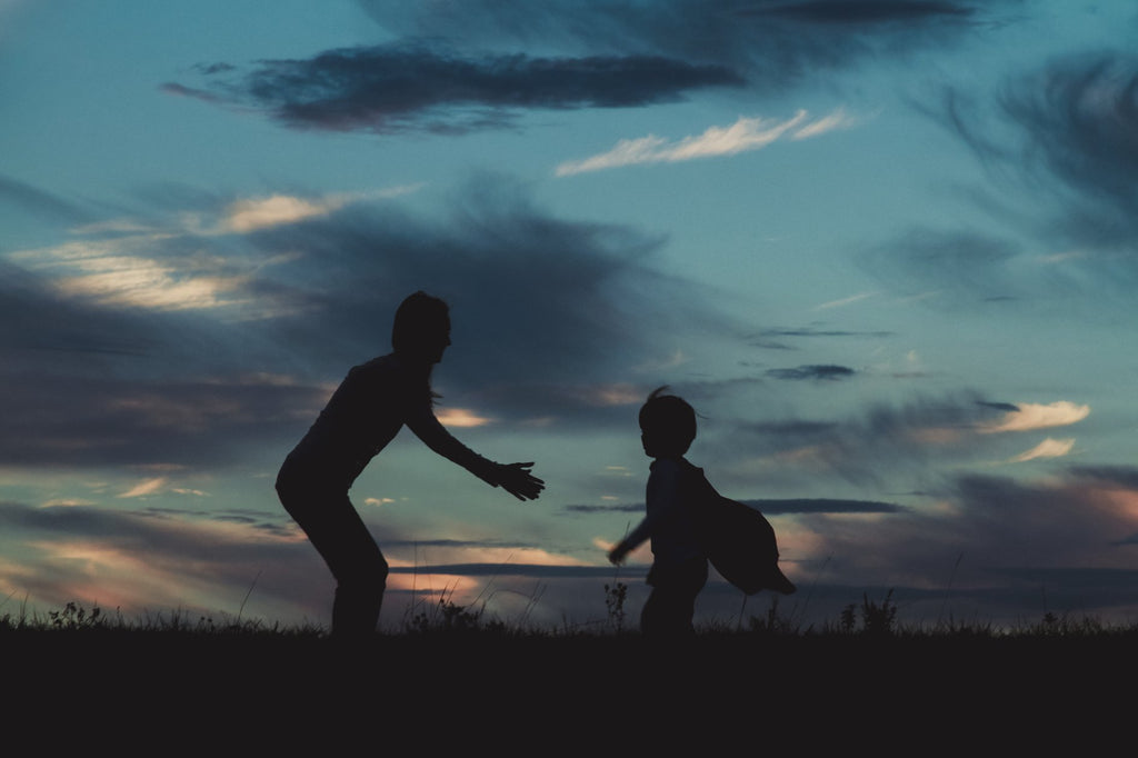 Silhouette of boy running into mother's arms