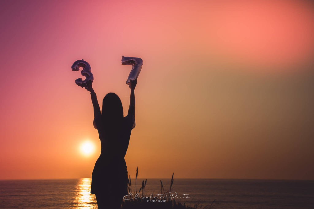 silhouette photo of woman holding birthday numbers in the air