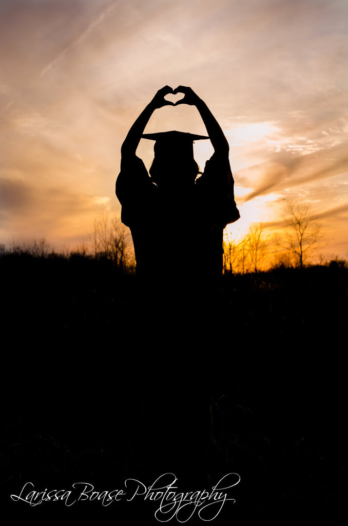 Silhouette photo of graduate holding heart above head