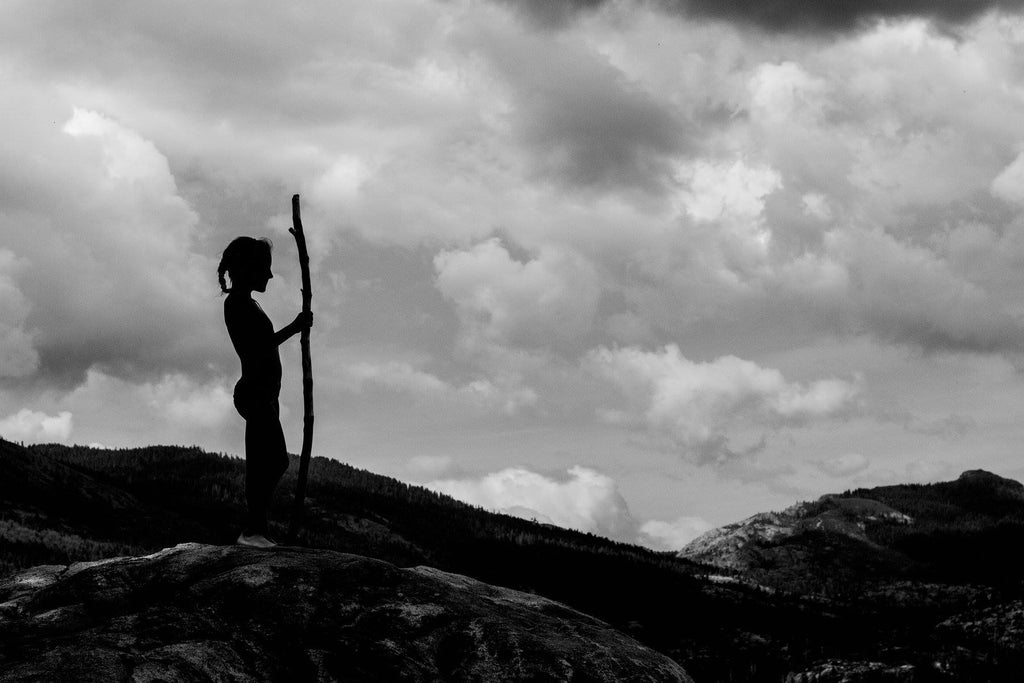 silhouette image of girl with stick on hill
