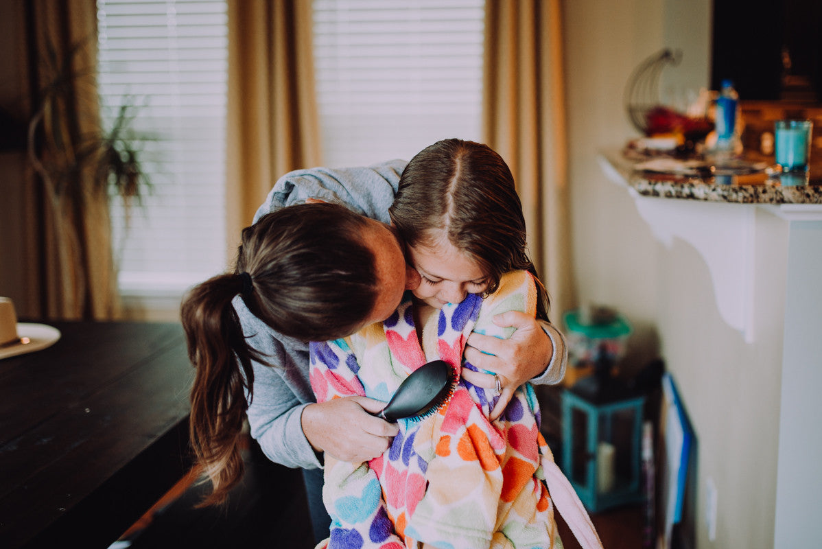 Mom combing daughters hair with a kiss
