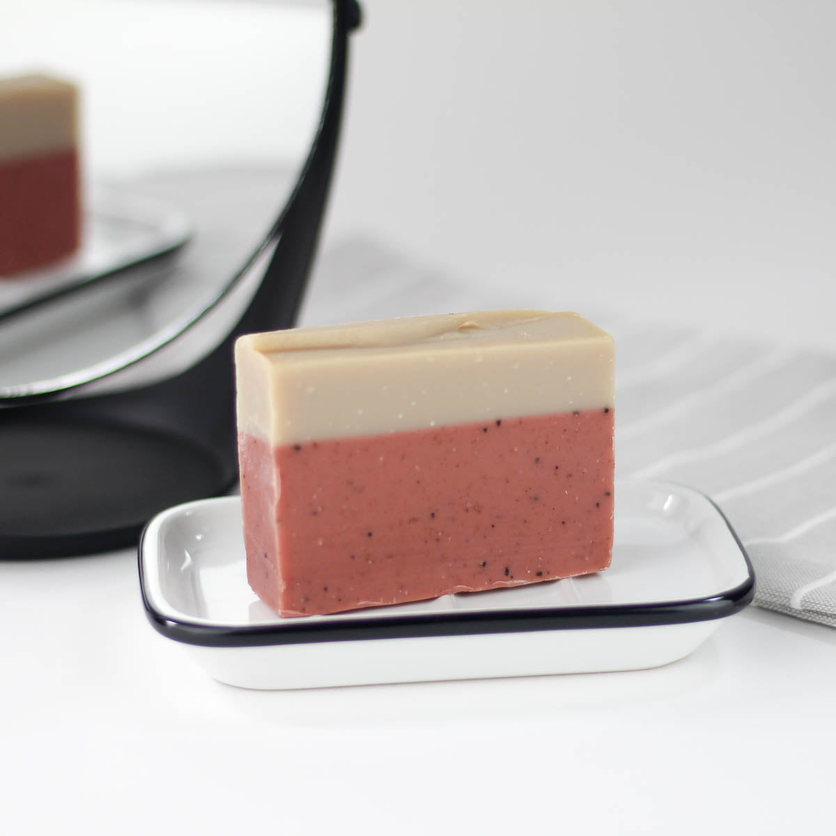 a two toned bar of soap sits upright on a soap dish in front of a mirror