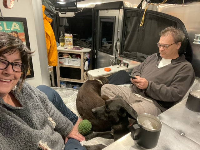 a woman, a man, and two dogs relax inside a well-outfitted camper trailer