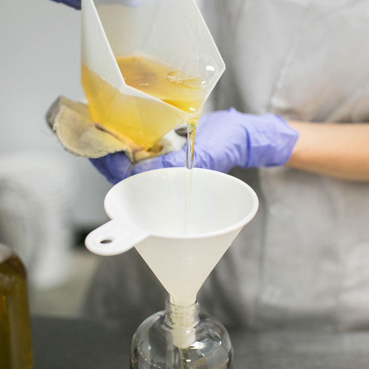 Bright yellow liquid soap poured into bottles with a funnel