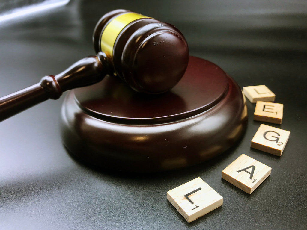 A judge's gavel next to scrabble tiles spelling the word 'legal'