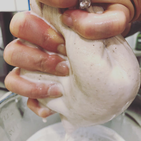 Michaline squeezing the almond milk out of a mesh bag