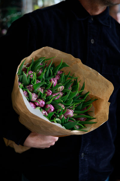 A bouquet of pink tulips wrapped in brown paper 