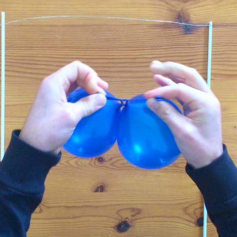 Tying mini blue balloons together for cake topper 
