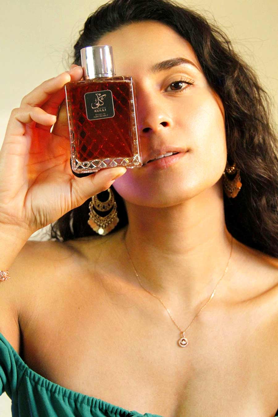 Headshot of woman holding perfume, Kulli Parfum, designed by Elias Feghaly.