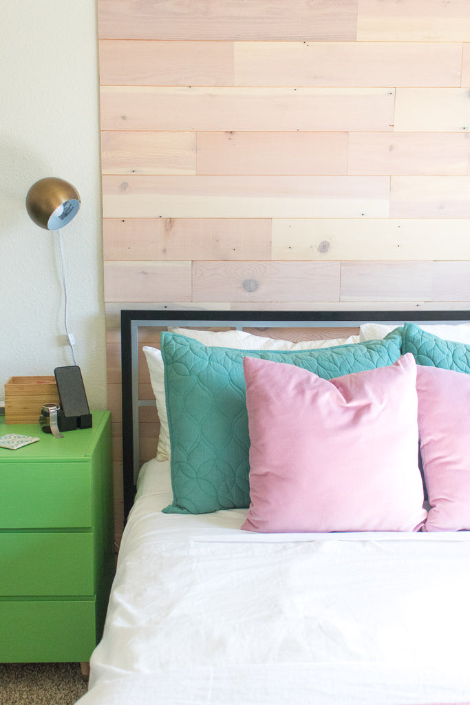 Pink-undertoned reclaimed timber wall behind bed works well with teal and pink pillows in teenage girl’s room.