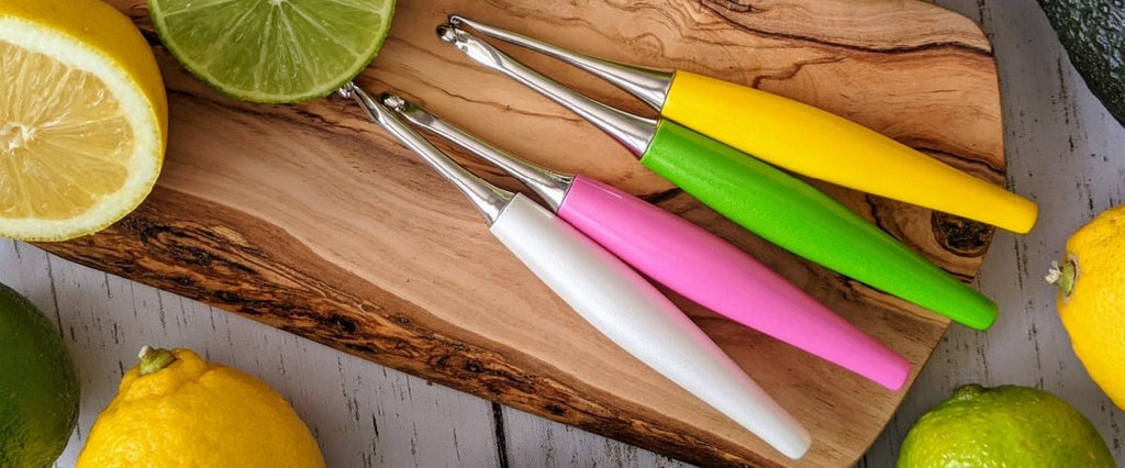 ODYSSEY CROCHET HOOKS  LAY ON A WOODEN BLOCK WITH LEMON AND LIME WEDGES