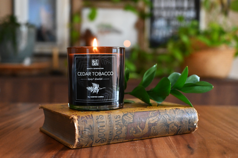 A lit candle in a brown glass jar sits on an antique book