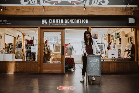 Stephanie Masterman, a woman in a white jacket with black hair, arranges a sign in front of the Eighth Generation store