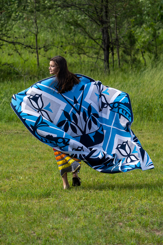 An Ojibwe woman walking away from the camera wearing the blue and white Good Life Blanket
