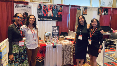 Four Native American women stand in front of a booth at the RES 2021 conference.
