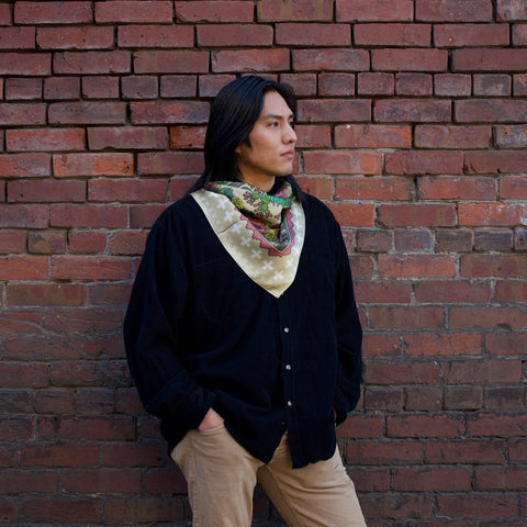 Cassius Johnson (Navajo) models our Desert Floral Silk Scarf against a brick background