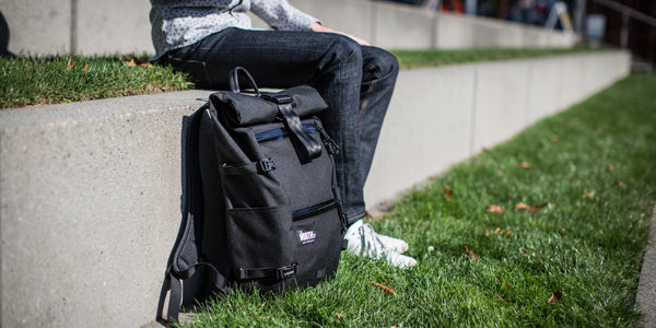 Man in park sitting with backpack. 