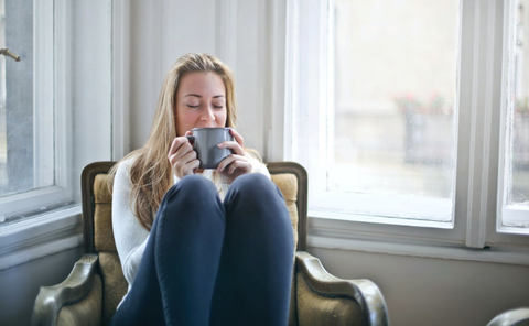 A woman holding a gray ceramic mug