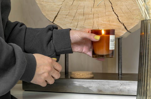 A person setting down a lighted-scented candle