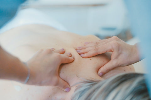 Two hands massaging the back of a person