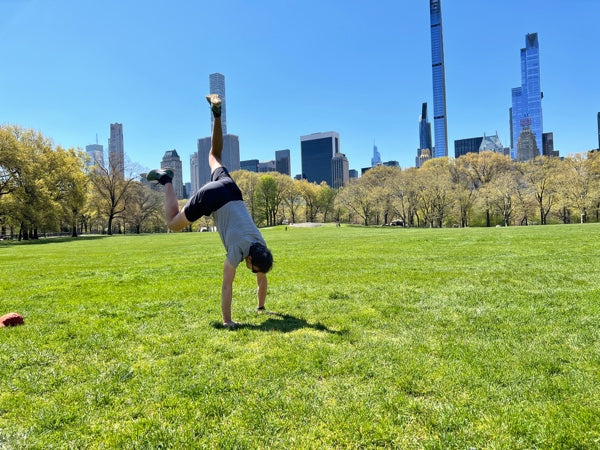 Stefan doing a handstand in Central Park wearing the Rev shorts, Threshold tee and Eardley cap.
