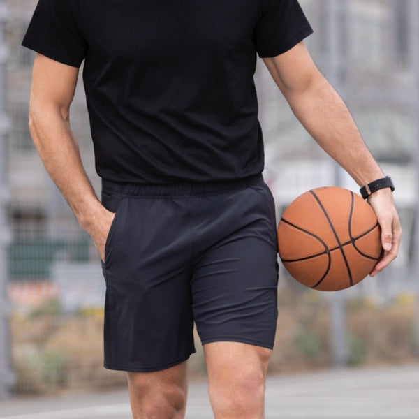 Man wearing Rev black athletic shorts holding basketball.