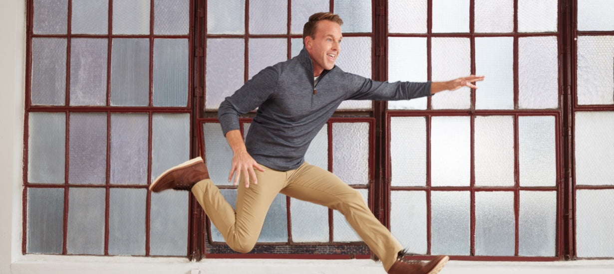 Model leaping while wearing khakis and the Como quarter zip pullover.